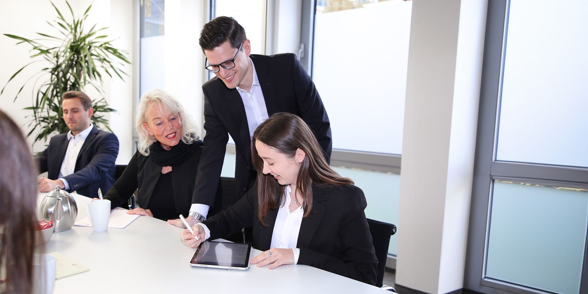 Herzlich willkommen bei ECOVIS KSO Menschen am Tisch in Besprechung mit iPad
